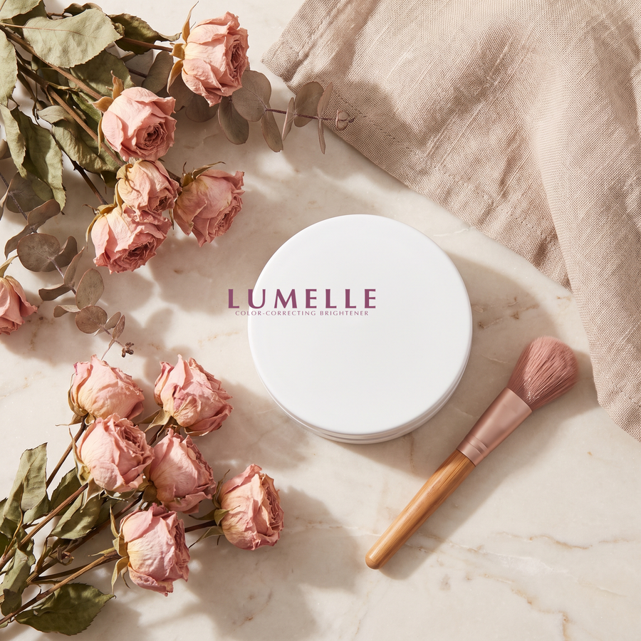 Lumelle undereye brightener compact styled on a vanity with roses and a brush